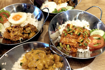 Pan-fried dish with a flavorful sauce, featuring tofu-like pieces and mixed vegetables over rice, served in a sizzling pan. Pan-fried dish with a flavorful sauce, featuring tofu-like pieces and mixed 