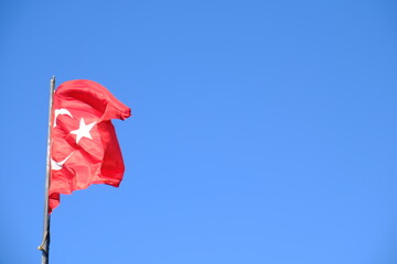 The Turkish Flag waving on the flagpole. The red Turkish Flag with star and crescent waves in the...