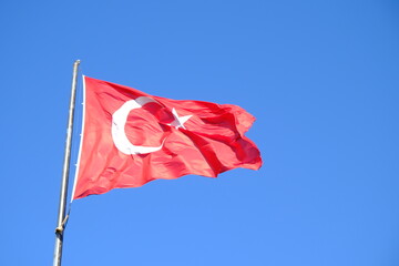 The Turkish Flag waving on the flagpole. The red Turkish Flag with star and crescent waves in the...