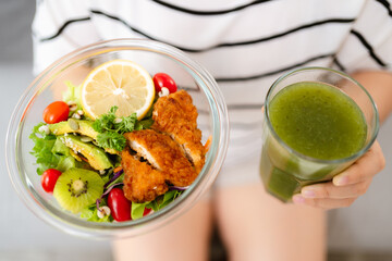 Beautiful Asian woman holding a bowl of salad and green vegetable and fruit juice. Healthy food