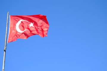The Turkish Flag waving on the flagpole. The red Turkish Flag with star and crescent waves in the blue sky. October 29, April 23, May 19, August 30, July 15. The flag of the Republic of Türkiye.