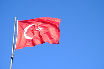 The Turkish Flag waving on the flagpole. The red Turkish Flag with star and crescent waves in the blue sky. October 29, April 23, May 19, August 30, July 15. The flag of the Republic of Türkiye.