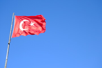 The Turkish Flag waving on the flagpole. The red Turkish Flag with star and crescent waves in the...