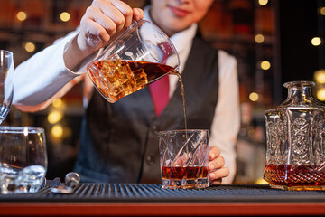 Professional female bartender preparing alcoholic drinks in a bar