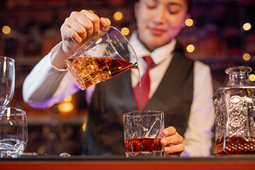 Professional female bartender preparing alcoholic drinks in a bar
