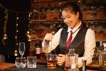 Professional female bartender preparing alcoholic drinks in a bar
