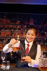 Professional female bartender preparing alcoholic drinks in a bar