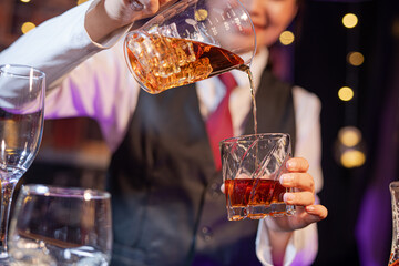 Professional female bartender preparing alcoholic drinks in a bar