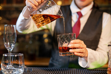 Professional female bartender preparing alcoholic drinks in a bar
