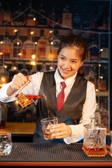 Professional female bartender preparing alcoholic drinks in a bar