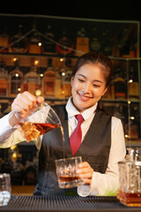 Professional female bartender preparing alcoholic drinks in a bar