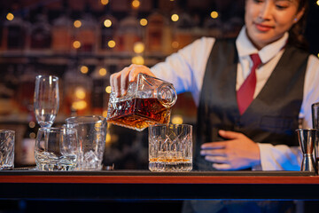 Professional female bartender preparing alcoholic drinks in a bar