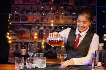 Professional female bartender preparing alcoholic drinks in a bar