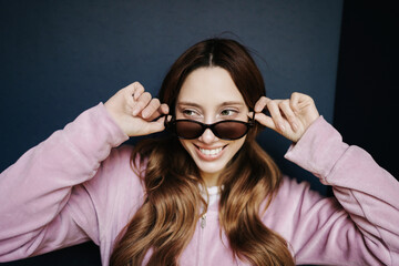 Stylish woman smiling and adjusting sunglasses in a fashionable urban portrait