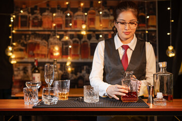 Professional female bartender preparing alcoholic drinks in a bar