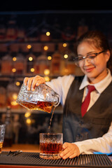Professional female bartender preparing alcoholic drinks in a bar