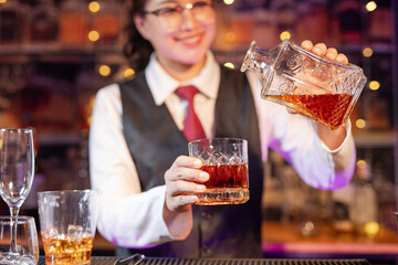 Professional female bartender preparing alcoholic drinks in a bar
