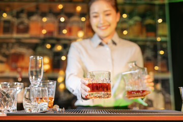Professional female bartender preparing alcoholic drinks in a bar