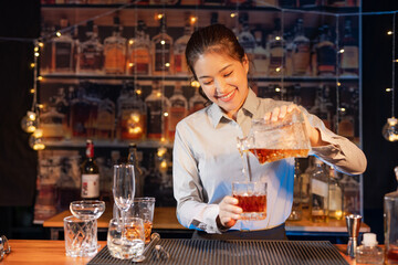 Professional female bartender preparing alcoholic drinks in a bar
