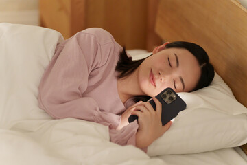 夜ベッドでスマホを使う女性