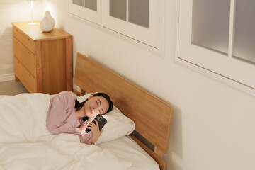 夜ベッドでスマホを使う女性
