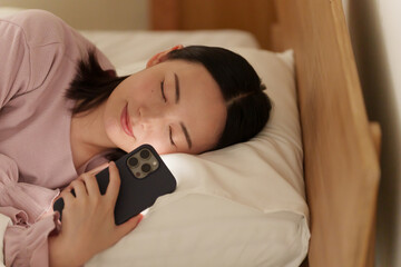 夜ベッドでスマホを使う女性