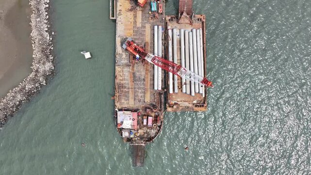 aerial view of the process of installing a giant sea wall by a large drilling machine on the north coast of Java Island