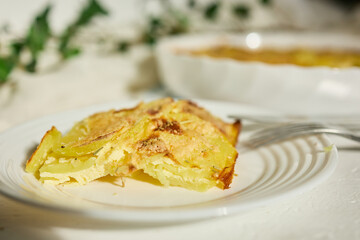 Delicious graten made with layers of sliced potatoes and cheese in a white rustic kitchen setting