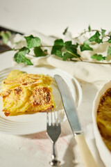Delicious graten made with layers of sliced potatoes and cheese in a white rustic kitchen setting