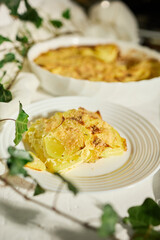 Delicious graten made with layers of sliced potatoes and cheese in a white rustic kitchen setting