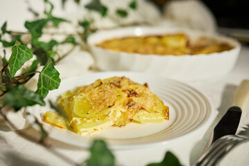 Delicious graten made with layers of sliced potatoes and cheese in a white rustic kitchen setting