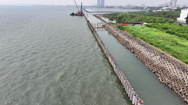 aerial view of the process of installing a giant sea wall by a large drilling machine on the north coast of Java Island