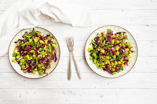 Quinoa and edamame salad with pomegranate seeds and mint on a white background