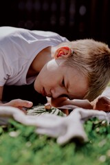 A boy with hearing aids gazes curiously at a snail on a leaf, capturing a magical childhood moment...