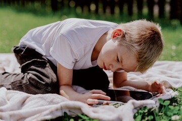 A boy with hearing aids gazes curiously at a snail on a leaf, capturing a magical childhood moment...