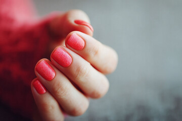 Closeup of a womans hand with stylish, shimmering red nail polish. Illustrates beauty, elegance, and attention to detail. Perfect for fashion, lifestyle, or selfcare themes.