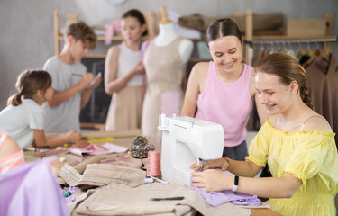 Child watches girl classmates work on creating clothes, school for young fashion designers and...