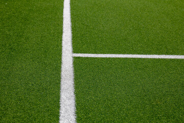 Artificial football field with crisp white markings on vivid green turf. Synthetic grass surface,...