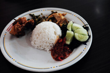 A classic Nasi Padang plate with rice, gulai curry, cassava leaves, young jackfruit gulai,...