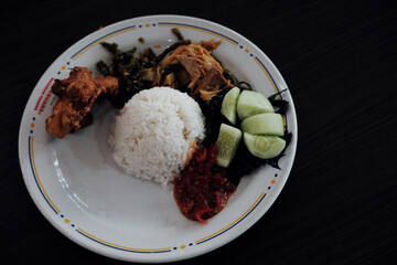 A classic Nasi Padang plate with rice, gulai curry, cassava leaves, young jackfruit gulai,...
