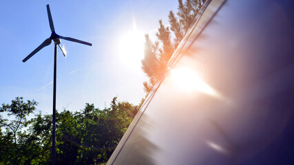 Solar panels with wind turbine on blue sky. Concept of clean energy. Green technology for future. 