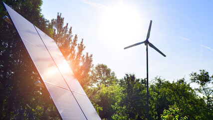 Solar panels with wind turbine on blue sky. Concept of clean energy. Green technology for future. 