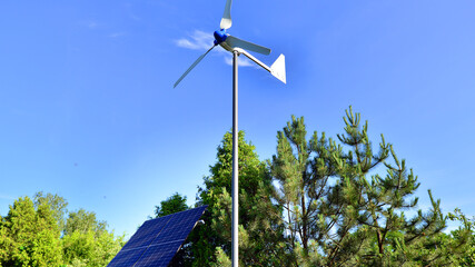Solar panels with wind turbine on blue sky. Concept of clean energy. Green technology for future. 