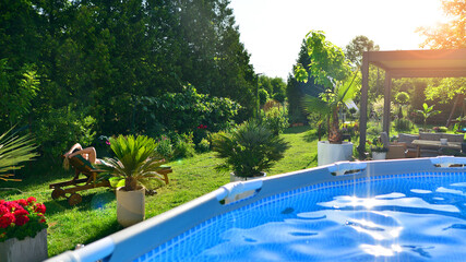 Modern aluminum pergola with stylish garden furniture in a beautiful garden. Swimming pool with...