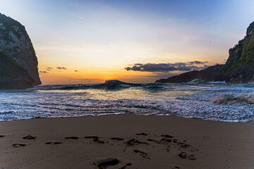 Aussicht auf den Sonnenuntergang bei rauem Wellengang am Kelingking Strand auf Bali in Indonesien.
