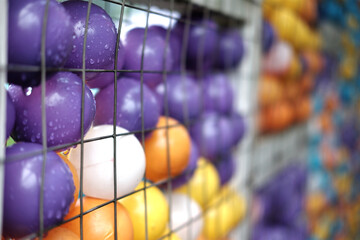A grid of colorful, water-splashed plastic balls, primarily purple, orange, white, and yellow,...