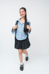 Young Southeast Asian student with blue striped long sleeves and black skirt walks forward toward...