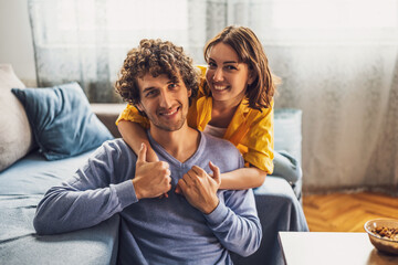 Portrait of young happy couple at home. They are looking at camera and smiling.