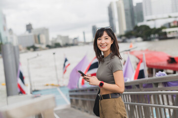 Smiling young southeast asian woman teenager blogger world travel explorer using smartphone...
