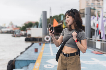 Solo southeast asian woman teenager blogger world travel explorer happy with smartphone. Wait for...